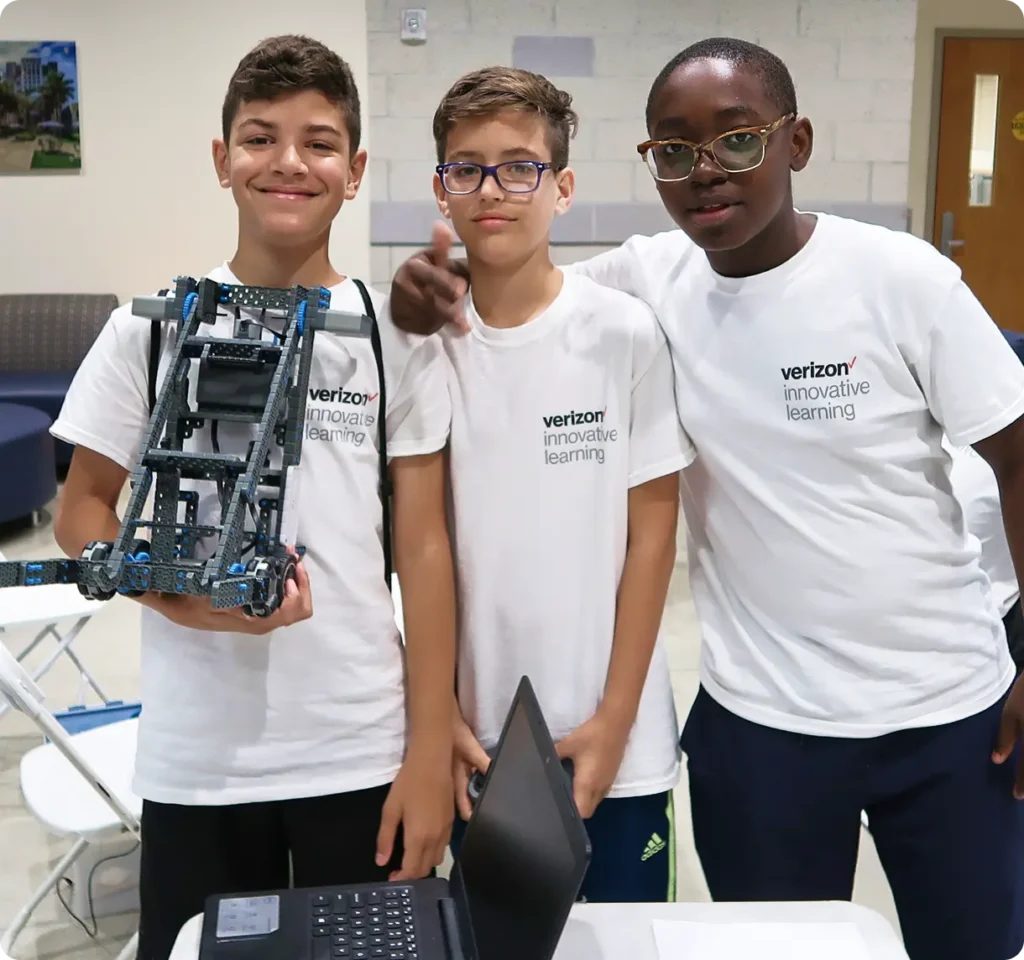 Three teenagers one is holding a robotic machine