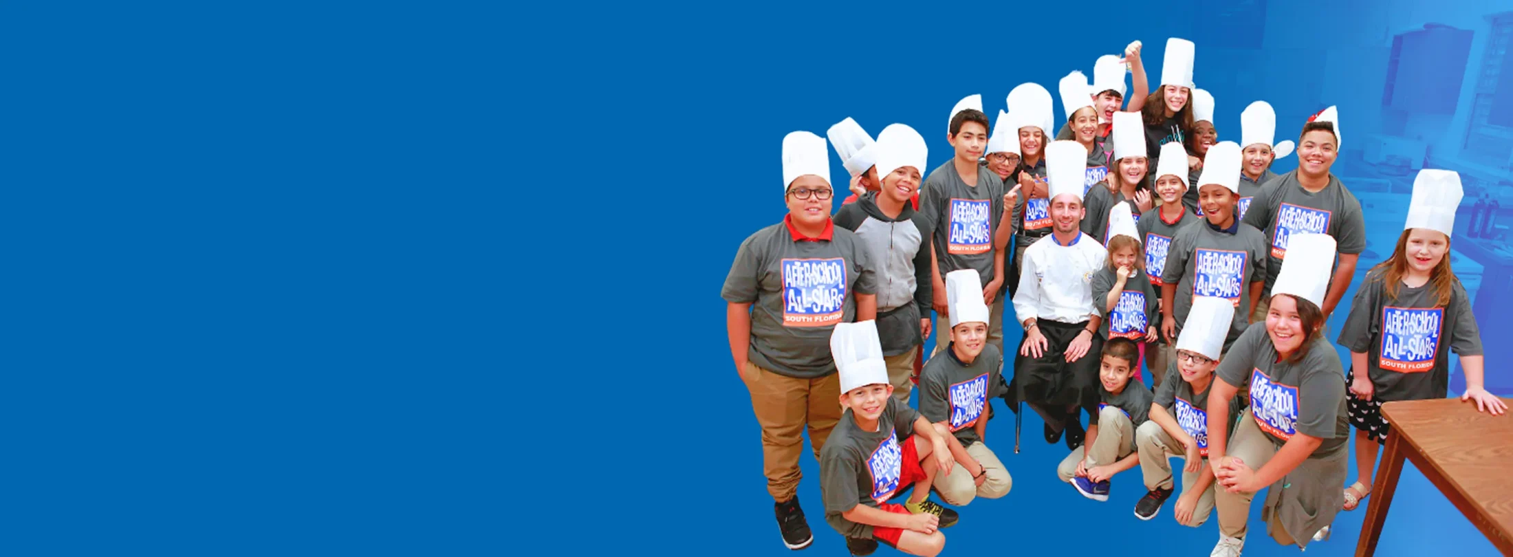 Group of kids wearing AfterSchool All-Stars shirts and white hats